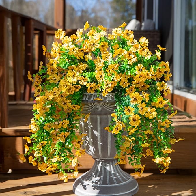 Yellow faux daisy hanging flower bundle in gray pot with trailing green leaves
