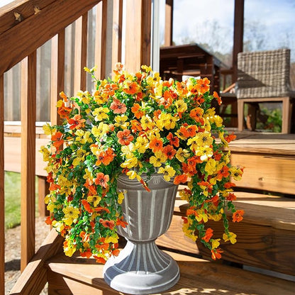 Artificial flower arrangement with orange and yellow blossoms and dangling green leaf strands