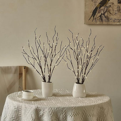 Brown lighted willow branches in white pots with warm white LEDs on a table runner