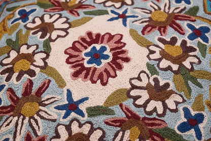 Multicolor flower and star embroidery on turquoise pillow cover, tight fabric close-up