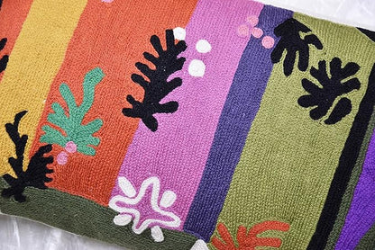 Close-up lumbar pillow cover embroidery with coral, purple, green, and black leaf motifs