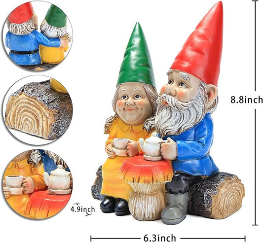Garden gnome couple figurines with blue and orange outfits, holding white mugs on log base