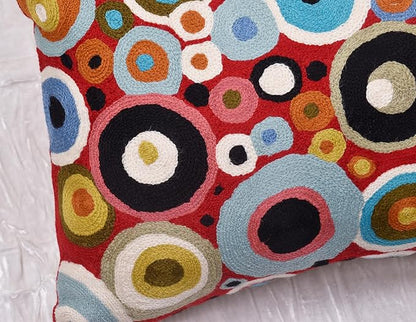 Red pillow cover front with layered rings in blue, black, and tan tones