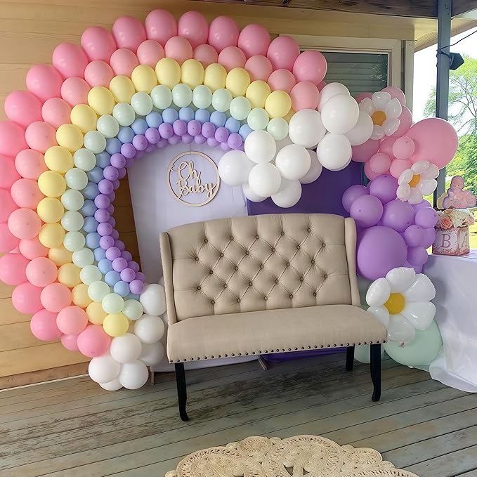 Rainbow balloon arch backdrop with pink, yellow, purple, and white balloon clusters