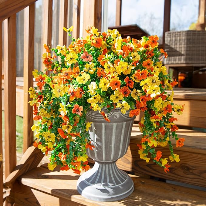 Artificial hanging flower bundle with orange and yellow blossoms and trailing green leaves