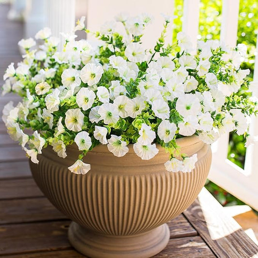 White faux morning glory flower arrangement with green leaves in a ribbed planter