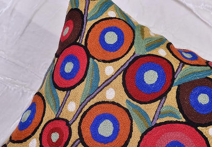 Embroidered wool pillow cover with bold circular designs in blue, red, and orange
