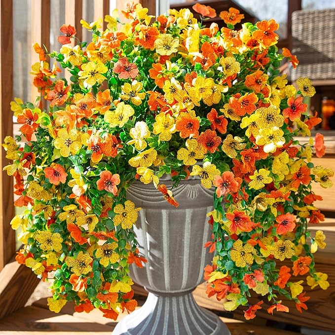 Artificial hanging flower bundles with orange and yellow blossoms and trailing green leaves