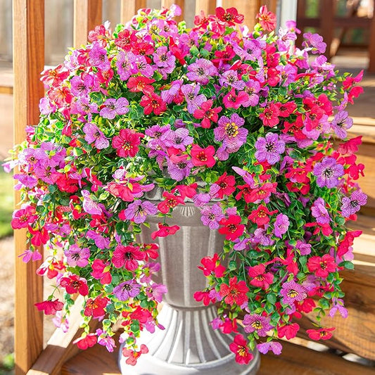 Purple and hot pink faux hanging flower bundles with trailing green leaves on display pot