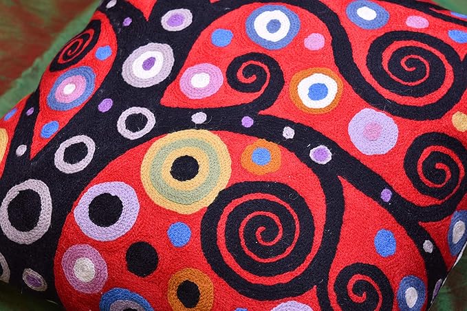 Red and black pillow cover with dense multicolor spiral, ring, and dot pattern.