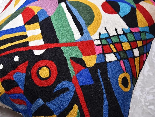 Black abstract embroidered pillow cover detail with multicolor geometric blocks and circles.