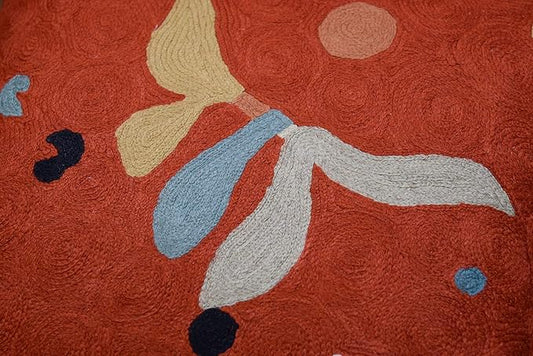 Close-up of orange abstract pillow cover with beige, blue and white petal shapes