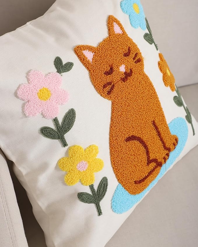 Close-up of cream cat throw pillow cover with embroidered orange cat and pastel flowers