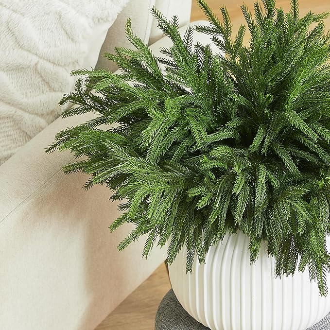Green faux pine branch stem with dense needles, in a ribbed white planter