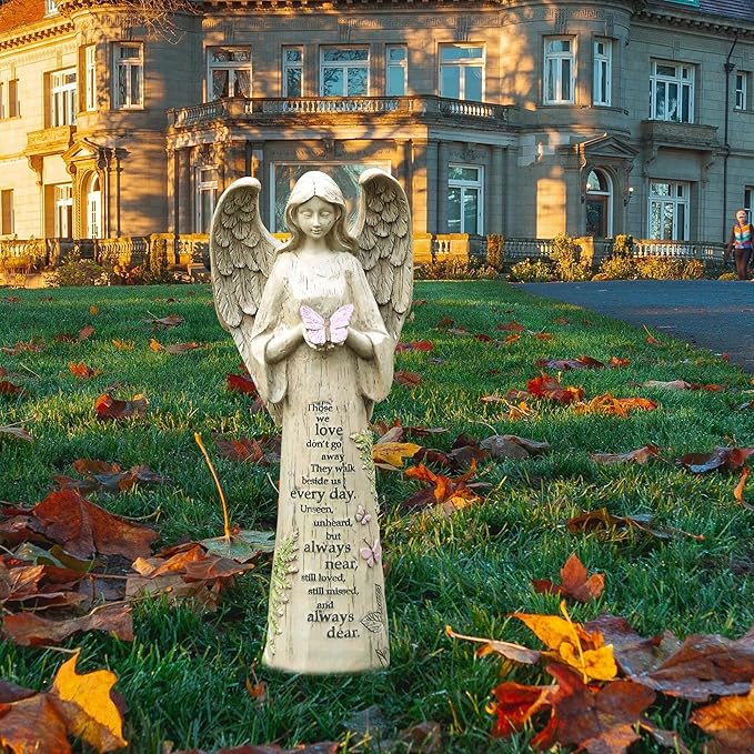 Outdoor resin angel statue with spread wings, a pink butterfly, and a memorial poem.