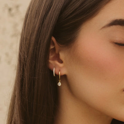 Gold diamond drop earrings with small hoop huggies on profile