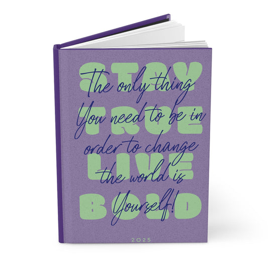 Hardcover journal with purple cover and green inspirational lettering; stacked pages visible.