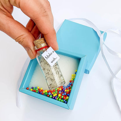 Open turquoise gift box with ribbon, miniature wish bottle jar with beads inside