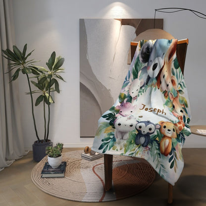 Safari animals blanket with name Joseph, draped on chair with leafy animal print on white