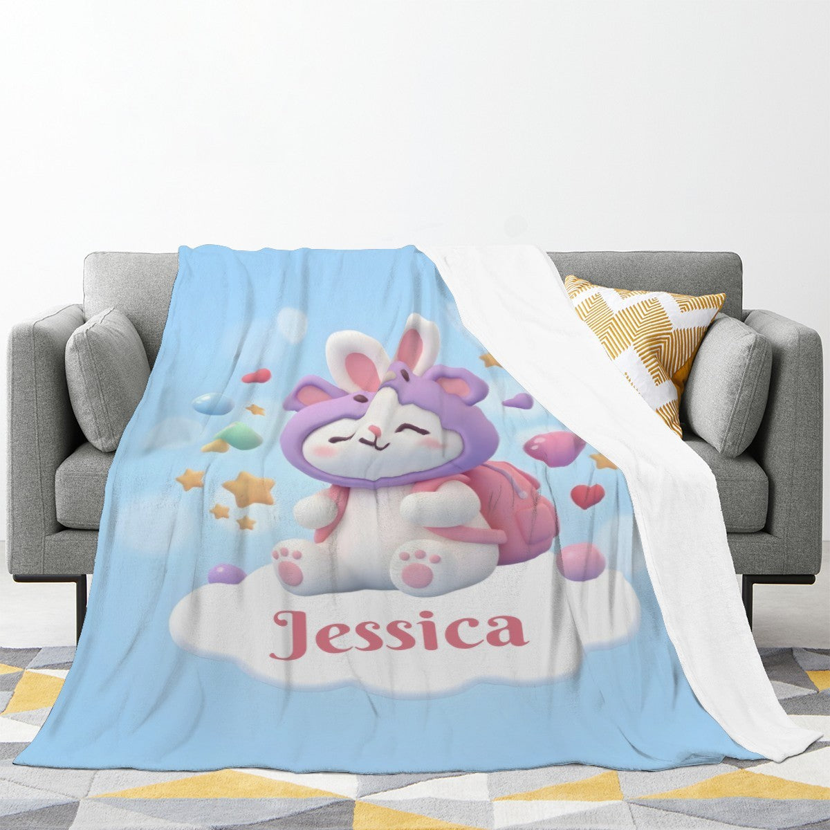 Light blue bunny-themed blanket draped on a sofa, showing “Jessica” lettering