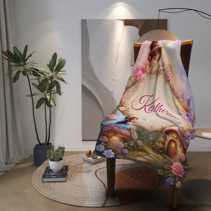 Personalized blanket draped over chair with “Katherine” script and fairy cottage scene