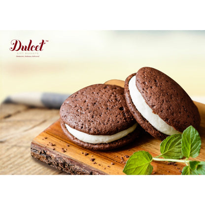 Chocolate sandwich cookies with white filling and mint leaves on wooden board