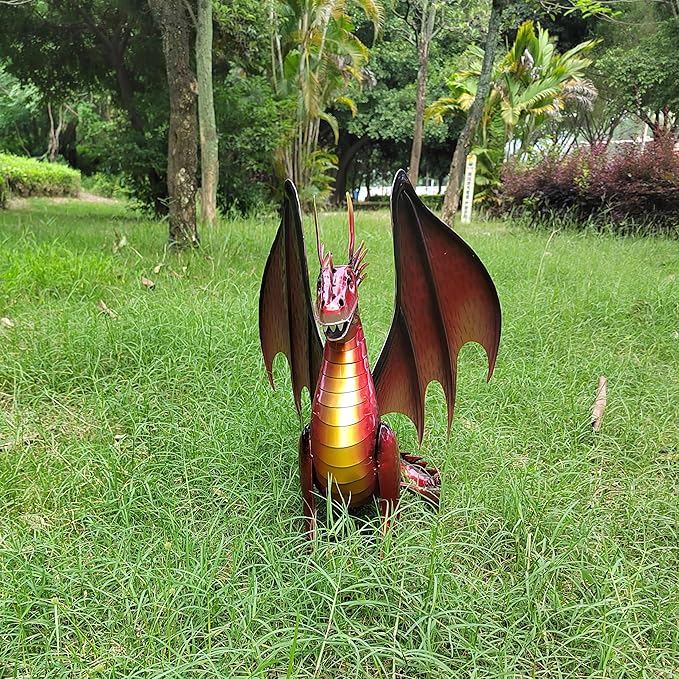 Red dragon statue seen from behind on grass, large wings and gold striped body