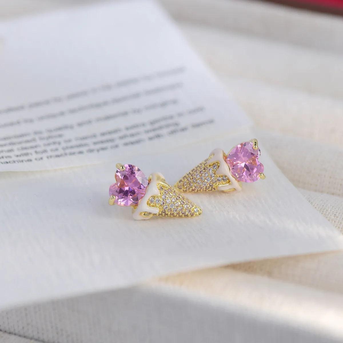 Pink heart and gold-tone triangular glitter earrings, side view on display