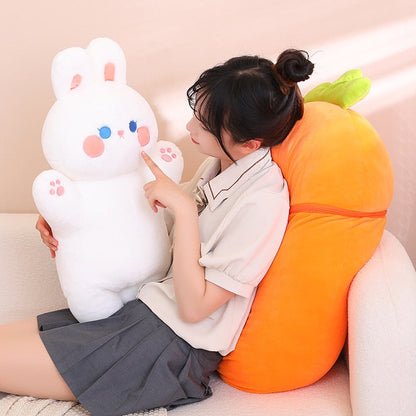 Two fruit animal plush toys: white bunny and orange carrot pig on a couch