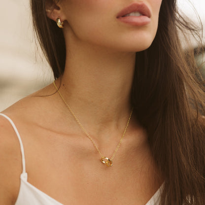 Gold-tone interlocking ring charm necklace resting on collarbone