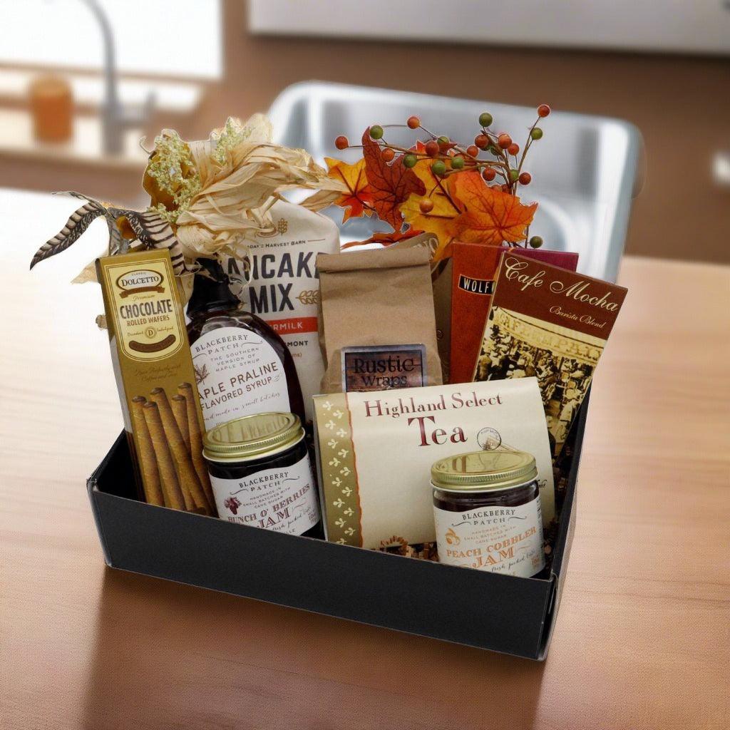 Breakfast gift box with assorted packaged breakfast items, tea, syrups, and leaf accents