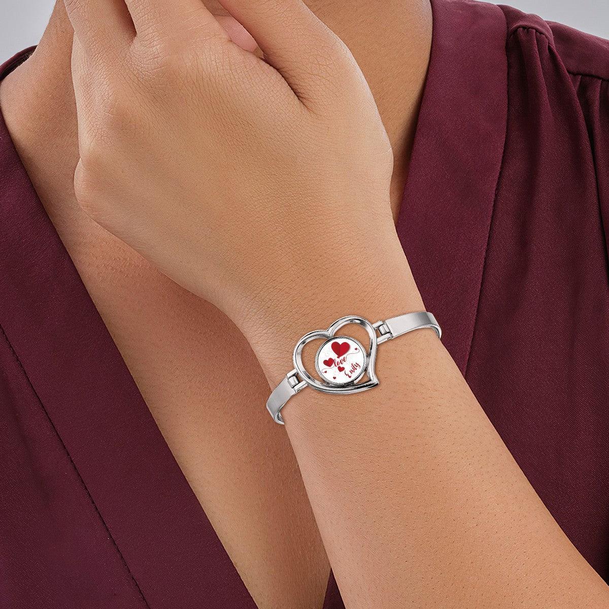 Heart charm bracelet on wrist with silver band and locket reading "Love Roselle"