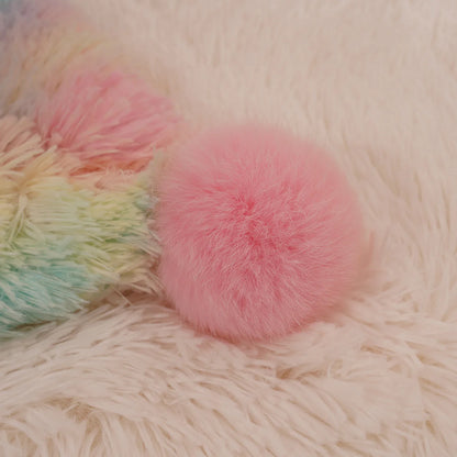 Soft pastel pom-pom on the corner of a fluffy rainbow blanket