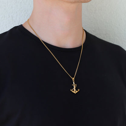 Gold anchor pendant necklace on a person, anchor charm centered on chest