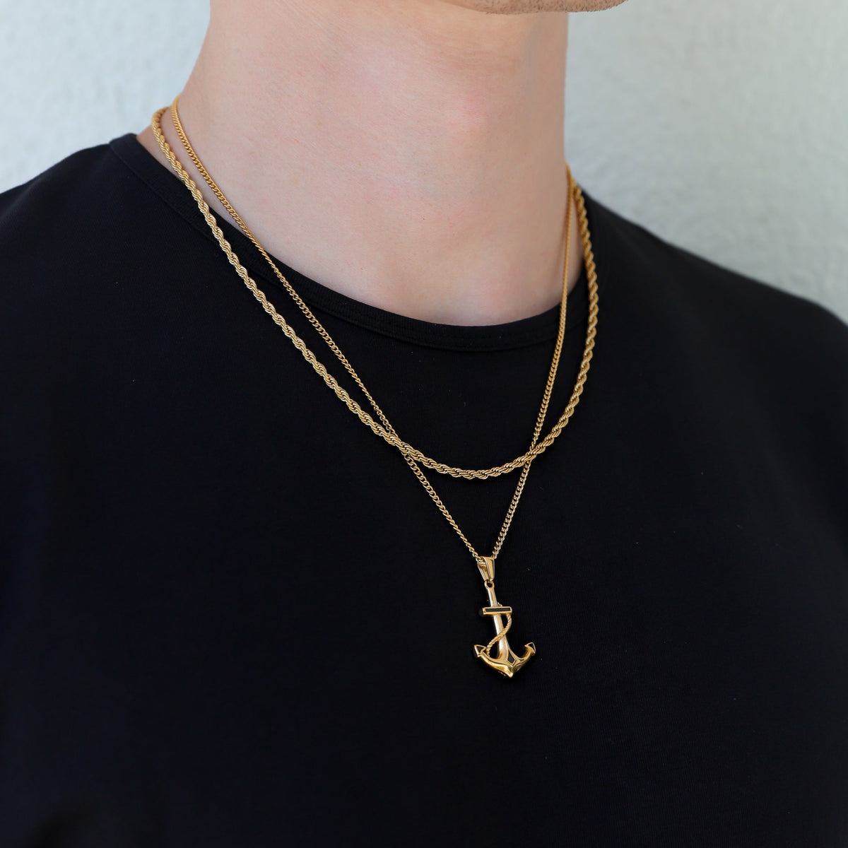 Gold anchor pendant necklace with layered chains, anchor charm angled downward