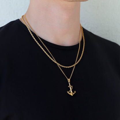Gold anchor pendant necklace with layered chains, anchor charm angled downward