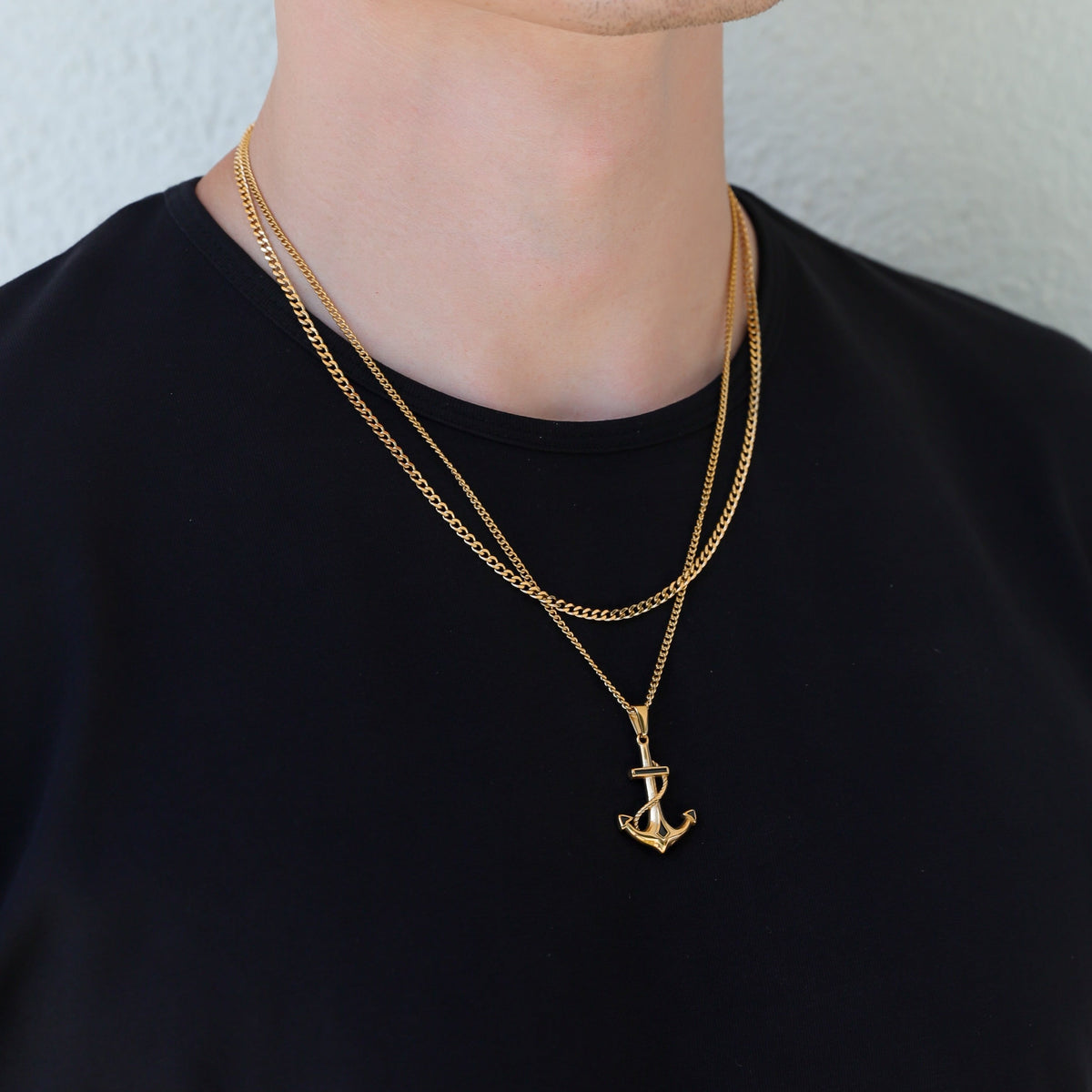 Gold anchor pendant necklace with a layered chain, anchor charm centered