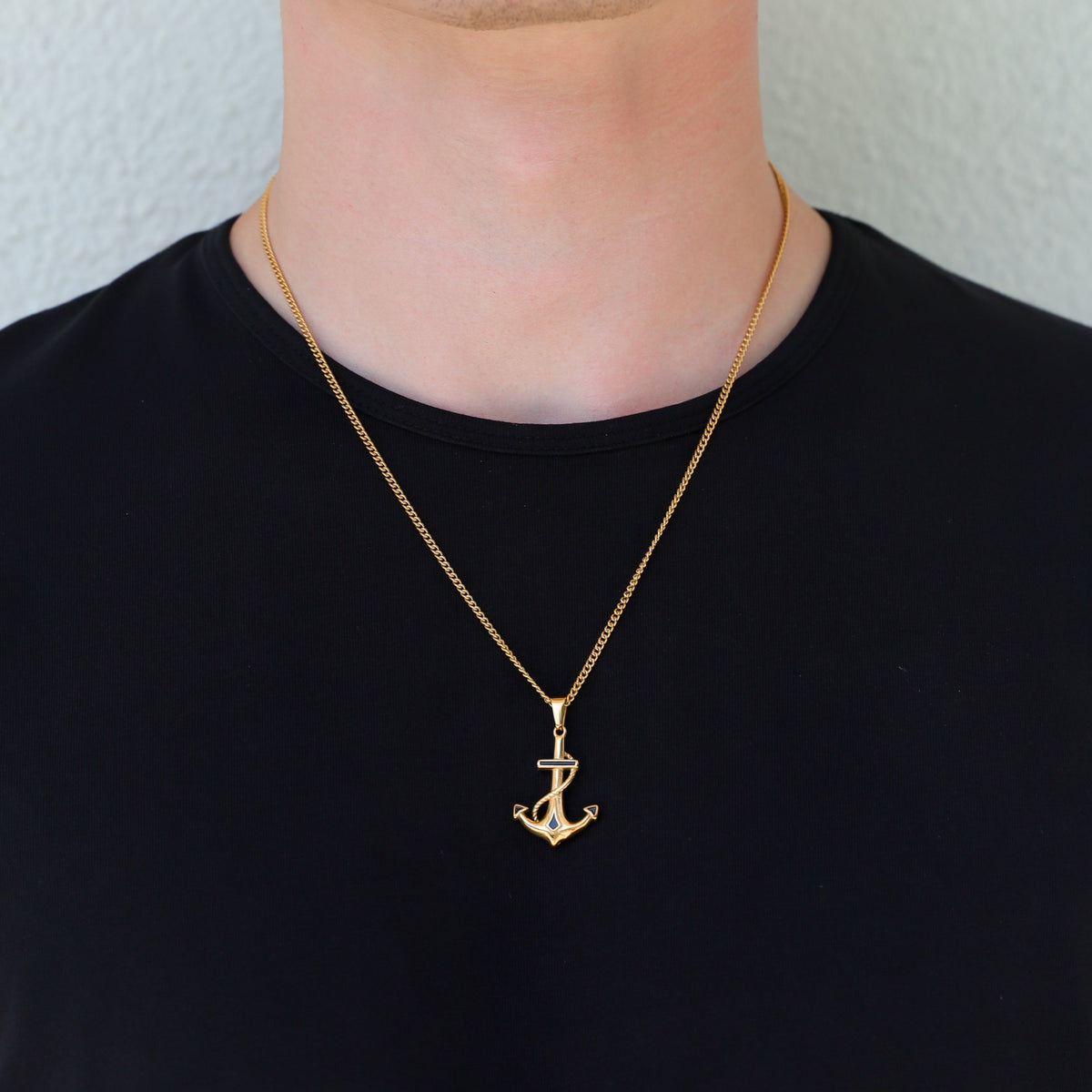 Gold anchor pendant necklace worn with single long chain, anchor charm visible