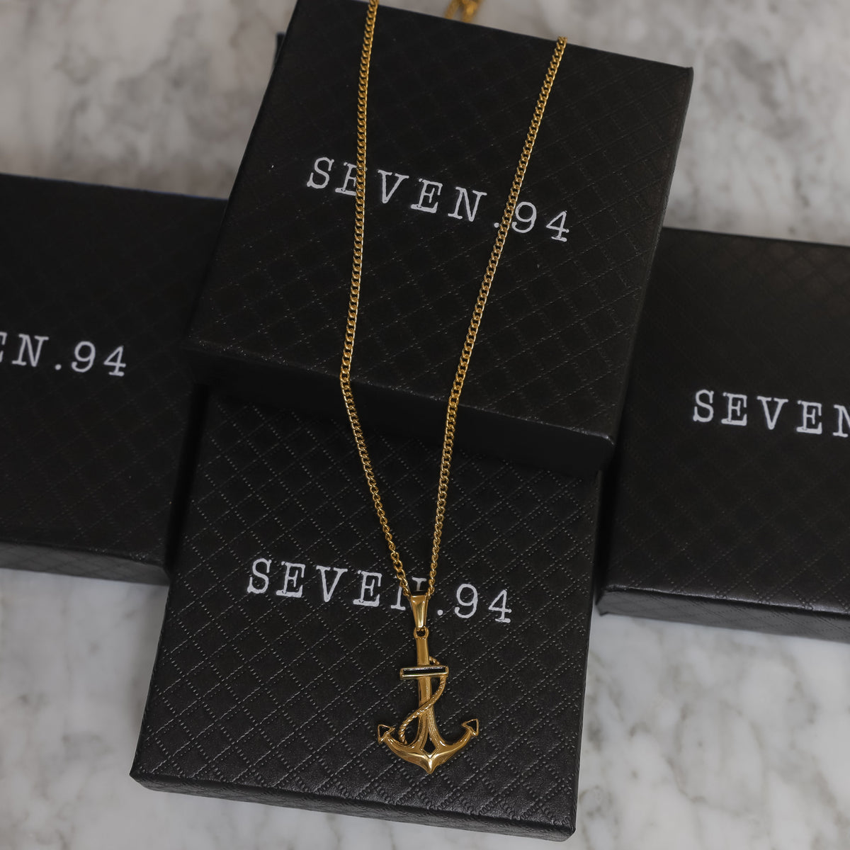 Gold anchor pendant necklace displayed, anchor charm on a long link chain