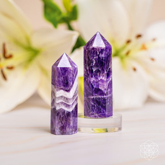 Two upright purple amethyst crystal points with faceted tops and white banding