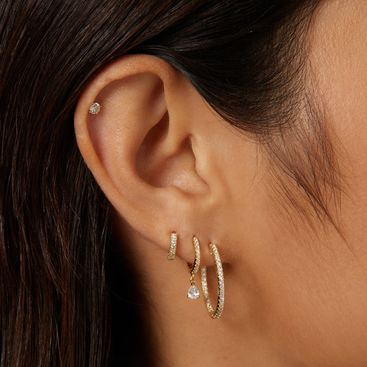 Diamond hoop earrings in gold with a small teardrop charm and a stud