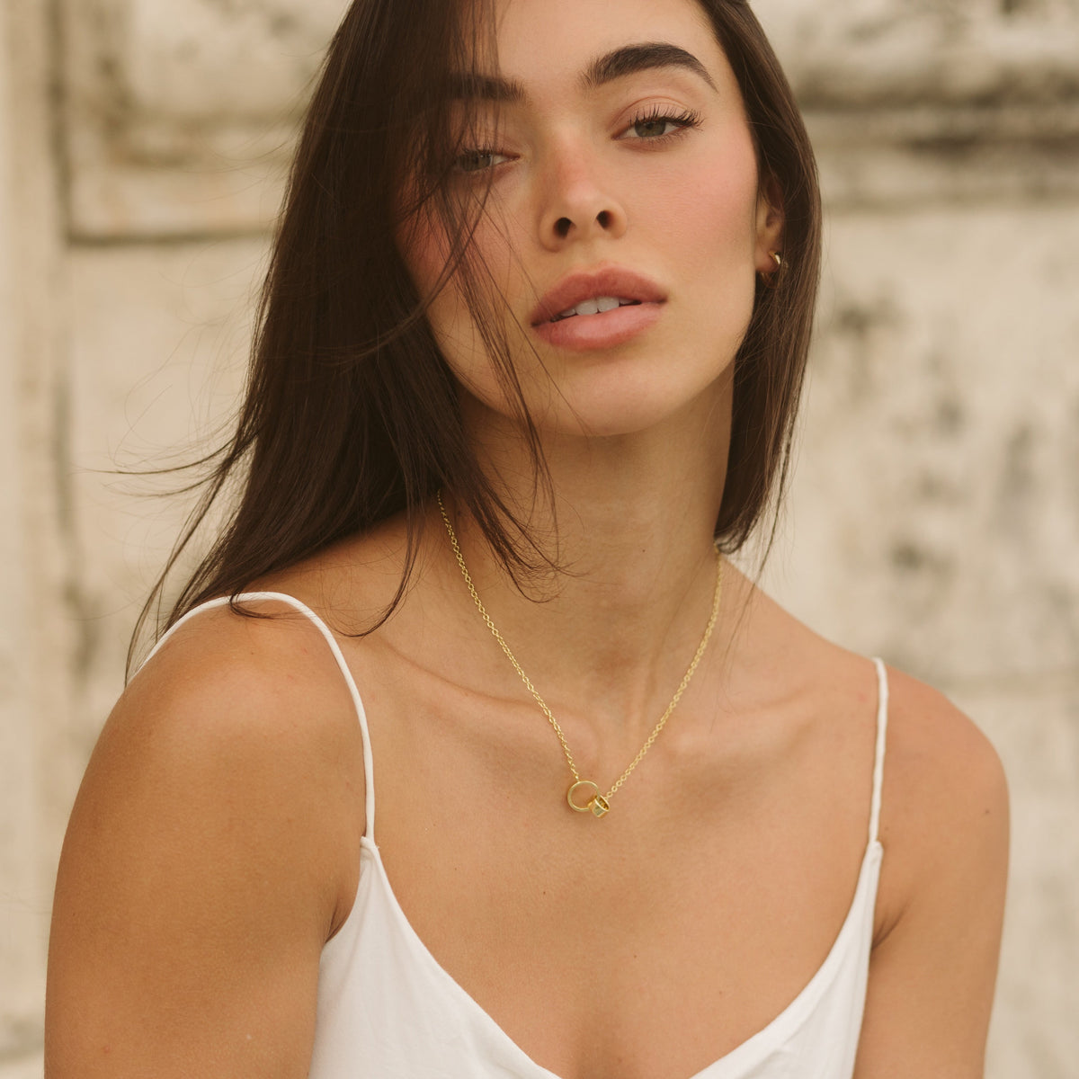 Gold-tone interlocking ring charm necklace worn by model