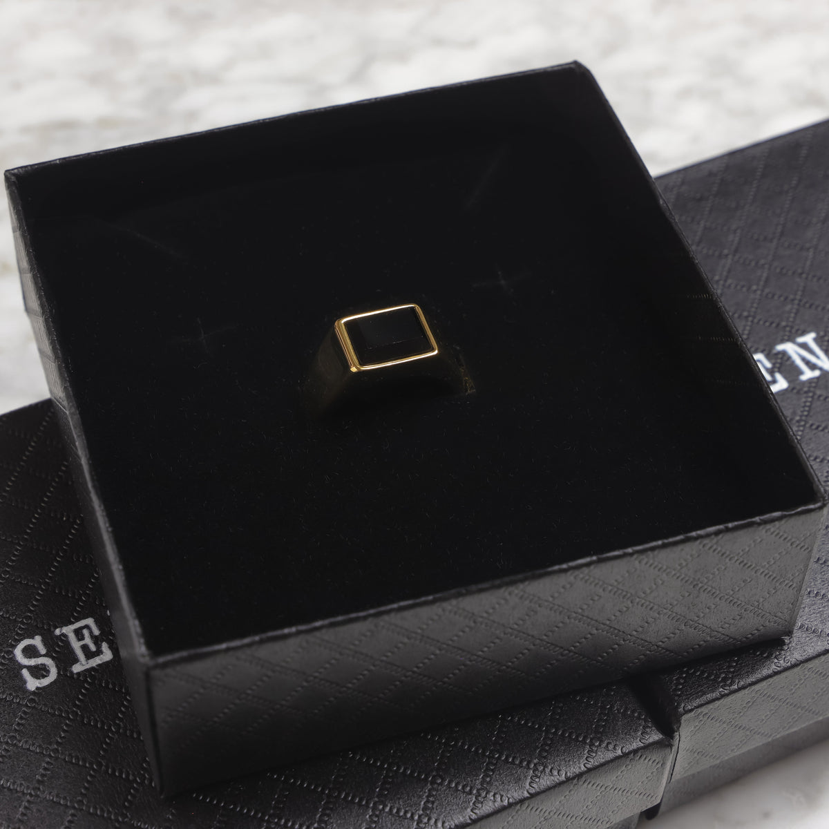 Square black signet ring on black display box insert