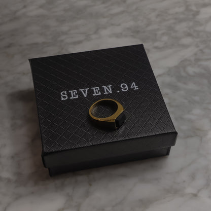 Square black signet ring resting on black gift box