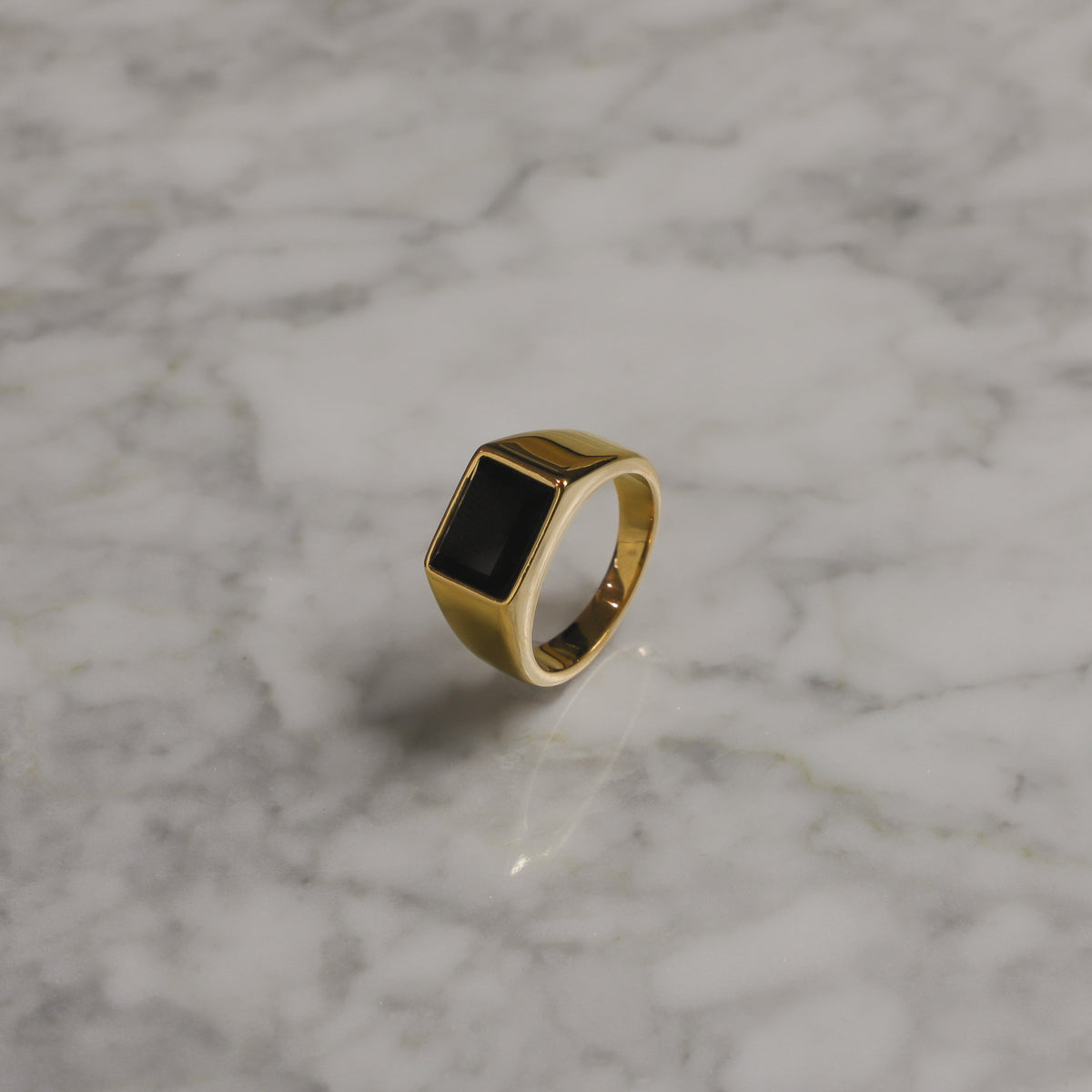 Square black signet stone on gold PVD ring, angled side view