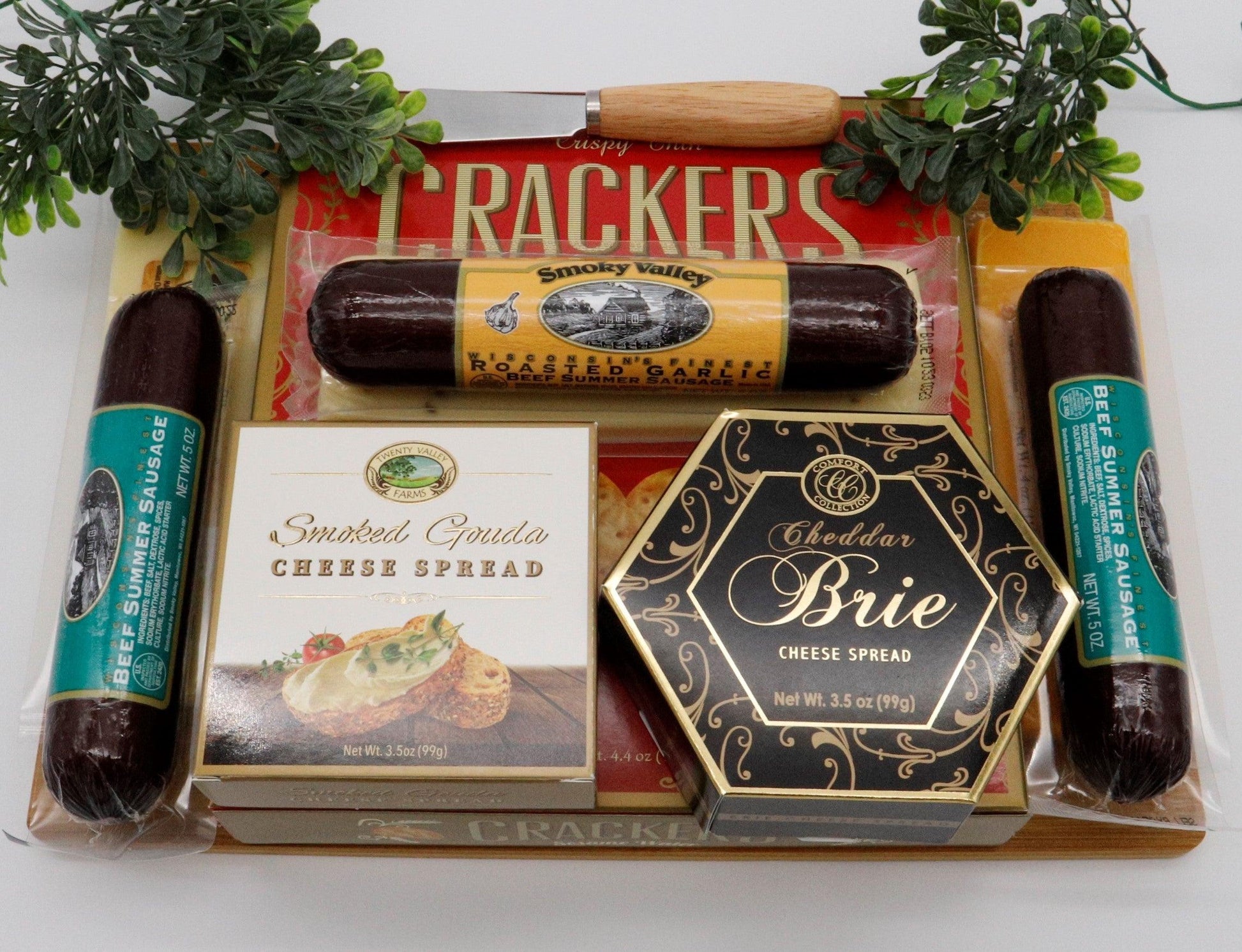 Wooden cutting board gift set arranged with crackers, cheese spreads, and sausage links