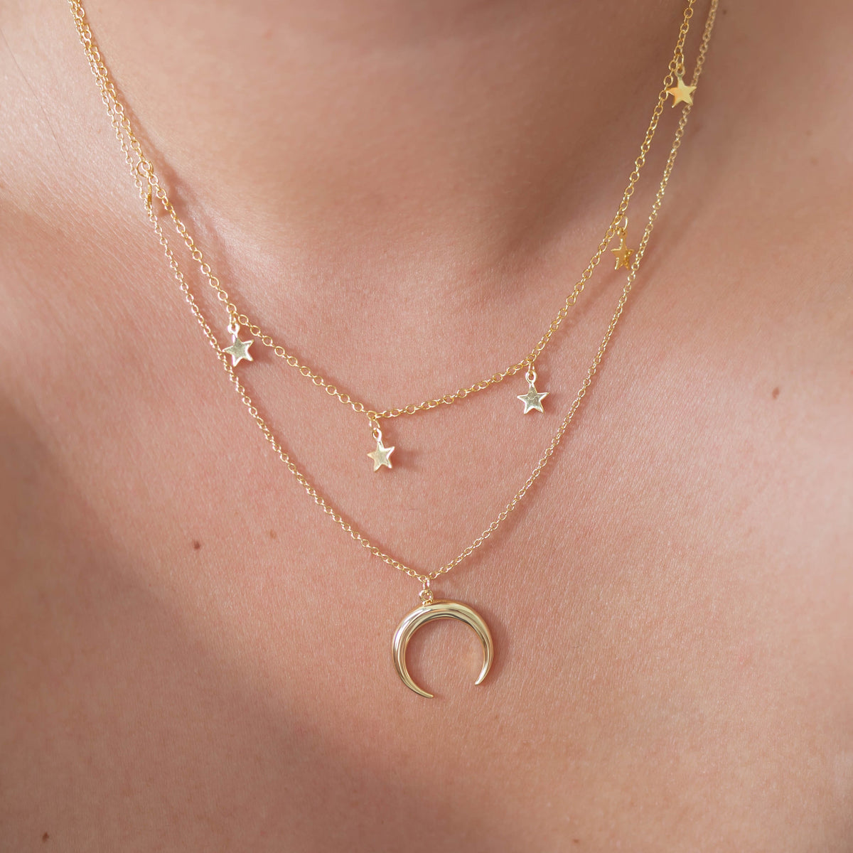 Gold layered star necklaces with crescent moon pendant on collarbones