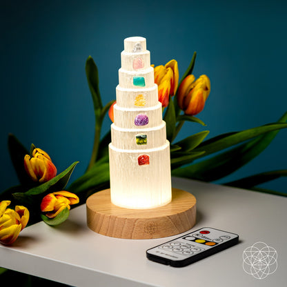Glowing stacked crystal lamp with multicolor stone insets on round wood base and remote