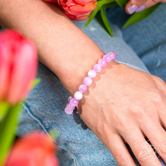 Pink gemstone bead bracelet worn on a wrist with short round beads.
