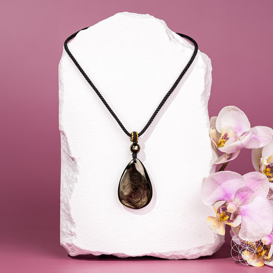 Teardrop pendant with dark iridescent stone on black cord, gold-toned accents.